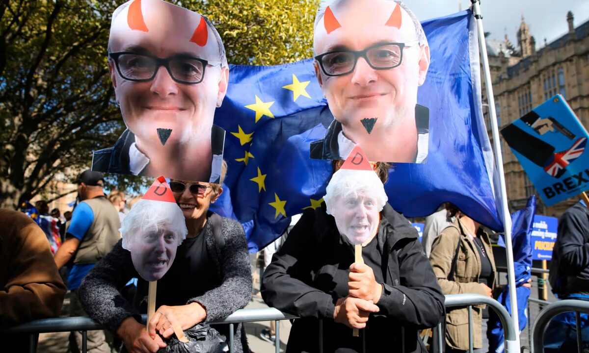Protesters at a pro-EU rally holding placards with defaced pictures of Dominic Cummings